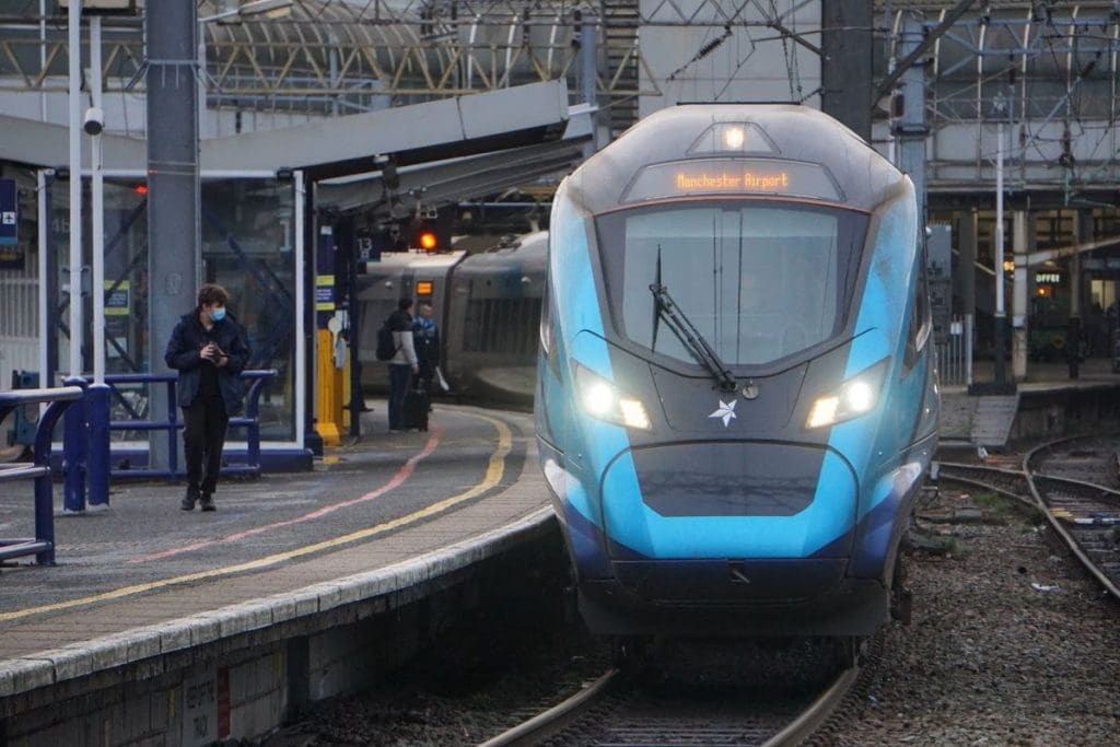 A train arriving at a platform at Manchester Piccadilly station.