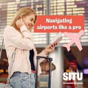 A woman with a suitcase looking at her ticket in an airport