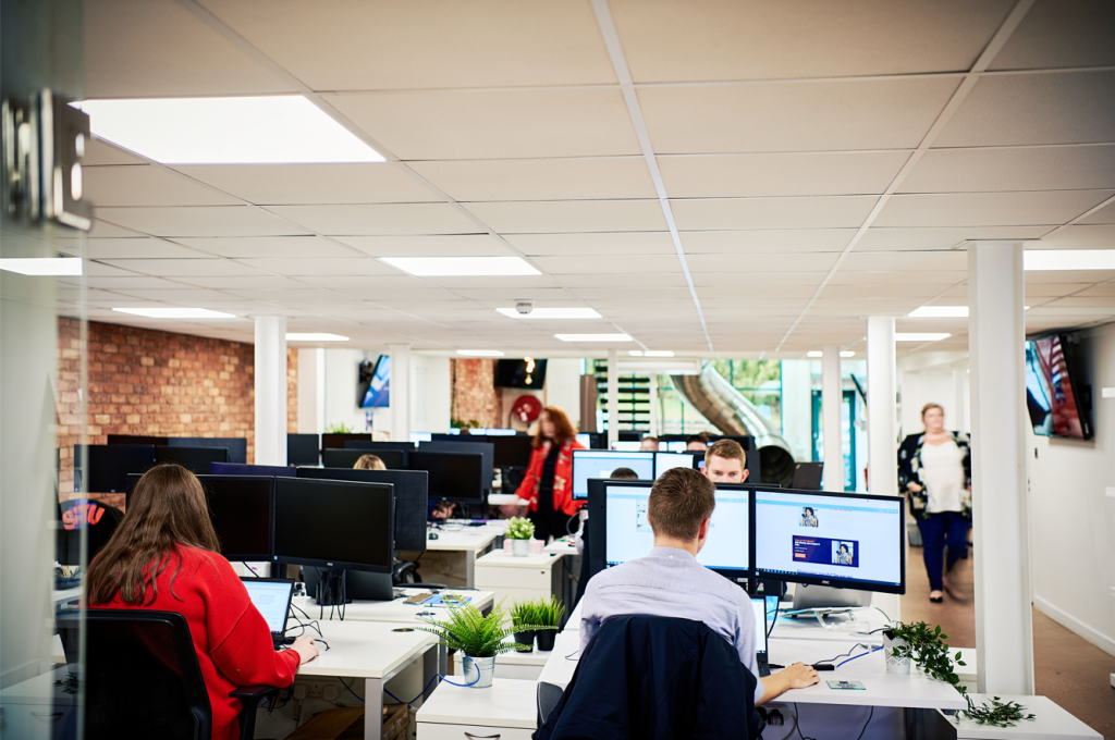 People sitting at desks looking at computers in an office.